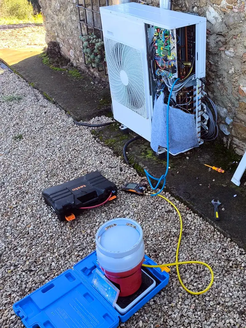 Unitat exterior oberta amb manòmetres i bàscula durant la càrrega de gas després d'una reparació